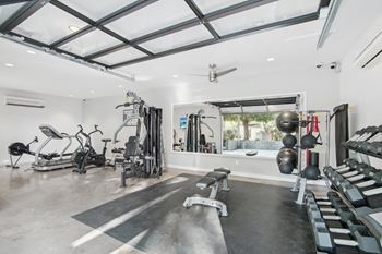 A spacious home gym with a variety of equipment including a treadmill, weights, and a bench.